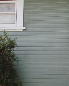 A residential home with different types of siding materials, including vinyl, wood, and brick, visible on its exterior walls.