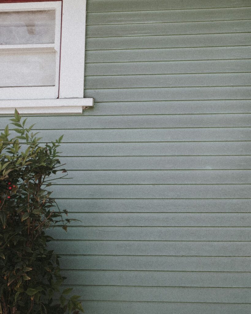 A residential home with different types of siding materials, including vinyl, wood, and brick, visible on its exterior walls.