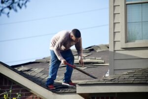 A close-up of a residential roof showing cracked and curling asphalt shingles on a sunny day.