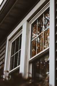 A person applying weatherstripping to a double-pane window in a residential living room.