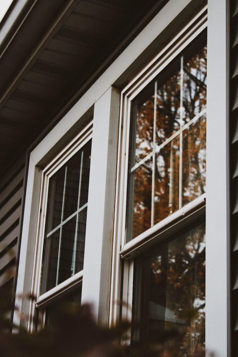 A person applying weatherstripping to a double-pane window in a residential living room.