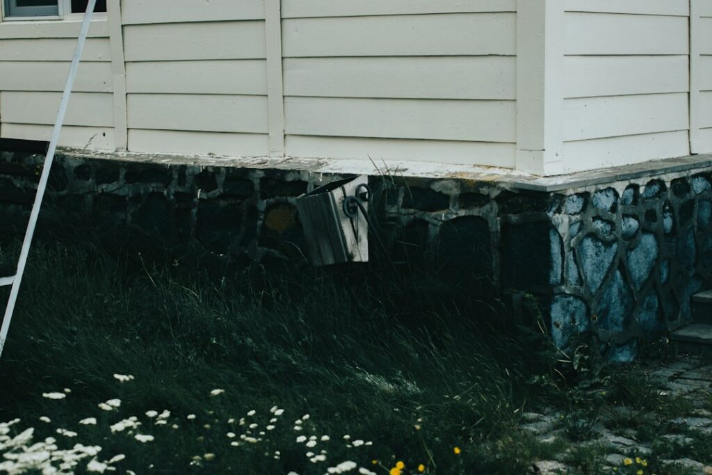 Homeowner examining a basement foundation wall with a flashlight and measuring a crack.