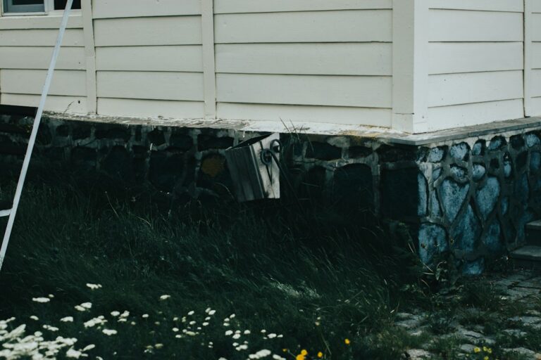 Homeowner examining a basement foundation wall with a flashlight and measuring a crack.